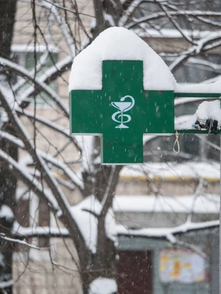 大雪过后 大绿色药店外部招牌霓虹灯轻十字标志覆盖着雪在雪移 — 图库照片