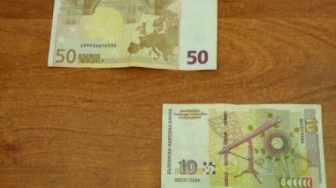 Motion animasyon 50 € ve 10 Bulgar Levası ahşap masanın üstüne bırak. farklı yönden hareket banknotlar için bir saniye ve daha sonra önünden hareketli ortasında buluş. closeup 4 k video ilmekledi
