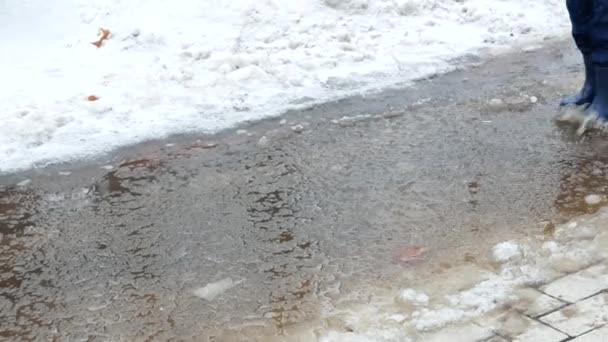 Μικρό παιδί σε αδιάβροχες μπότες περπάτημα στη λακκούβα — Αρχείο Βίντεο