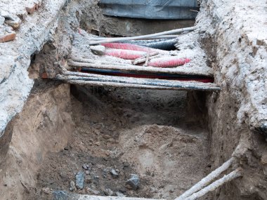 Hendek su boruları ve elektrik telleri zemin çukur siperde sırasında tesisat inşaat onarım altında. yatay görüntü