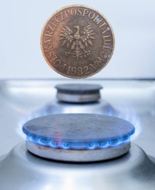 one old vintage Poland coin zloty over gas burner. utility costs in Europe concept
