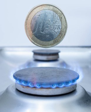 one euro coin over gas burner. utility costs in Europe concept