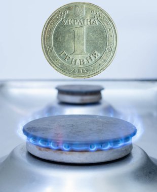 one Ukrainian coin hryvnia over gas burner. gas import, export or utility costs in Europe concept