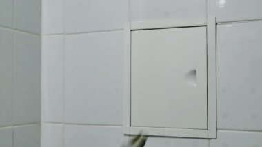 Tesisatçı anahtar ile banyoda boru hattı için küçük kapıyı aç. Sadece el ile anahtar görünür