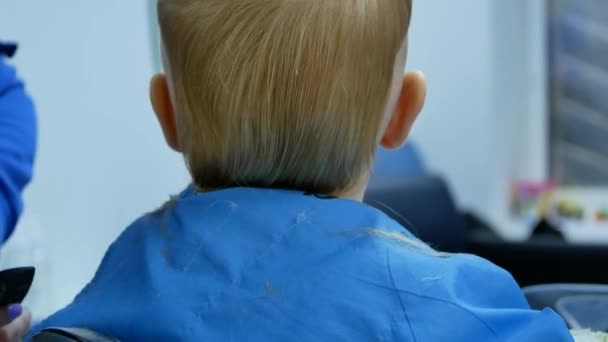 理发师试图剪掉头发用剪刀从后头可爱的2岁小男孩 而他旋转他的头 从后面近距离观看4K 视频画面 — 图库视频影像