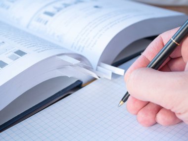 yan görünümü kalemini kare içinde bir not defteri boş çarşafları üzerinde öğrenci yardım ve arka plan üzerinde yer imleri ile bulanık kitap. yakın çekim düşük açısı Shot