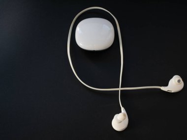 siyah arka plan üzerine plastik kutu ile küçük beyaz kablosuz kulaklıkları. taşınabilir müzik konsepti