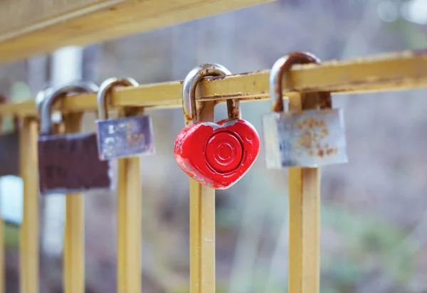Zamki do drzwi wiszące na metalowe ogrodzenie na most miłości. Selektywny fokus na jedna kłódka w kształcie serca czerwone kolorowe jako symbol romantyczny spraw — Zdjęcie stockowe