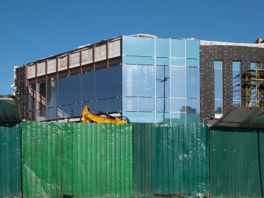 Yeşil çit önünde inşaat alanında. küçük ofis binası veya townhouse cam, metal ve beton