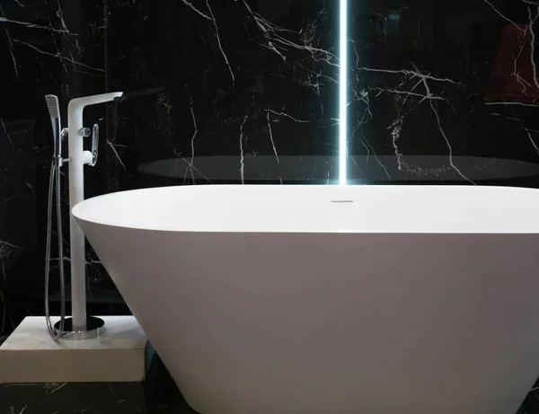 背景に黒い大理石の壁が付いているホテルのアパートの現代白い浴槽。バスルームで現代的なインテリアデザイン — ストック写真
