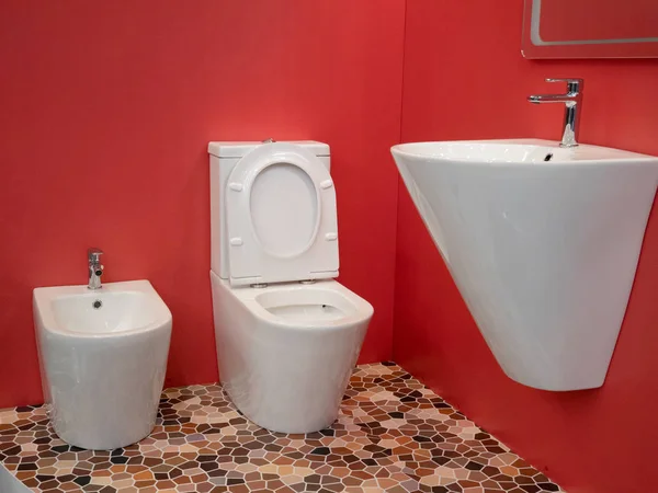 Μοντέρνο εσωτερικό μπάνιο εσωτερικού σχεδιασμού με λευκό νιπτήρα, τουαλέτα, μπιντέ και ζωηρά κόκκινα τείχη — Φωτογραφία Αρχείου