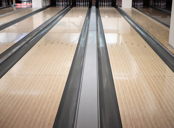 Dua jalur trek di klub bowling dengan sekelompok mangkuk pin pada jarak jauh. gambar sudut rendah Stok Lukisan  