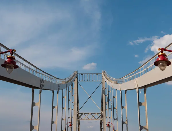 Kırmızı modern şehir fenerleri ile demir köprü. derin perspektif, köprü sütunları arka planda mavi gökyüzüne yol açar. — Stok fotoğraf