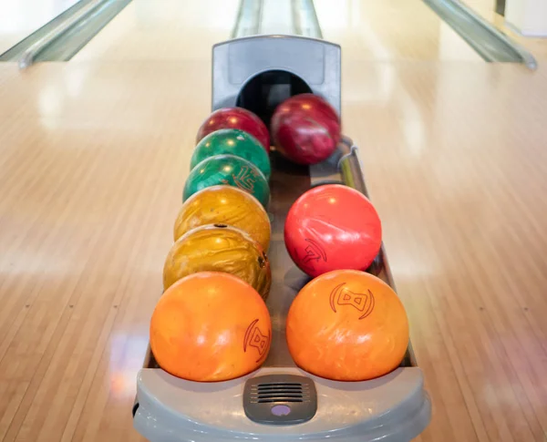 group of colorful balls at bowling club. nobody in the frame. family recreational leisure activity concept. one blurred ball rolling out of black hole