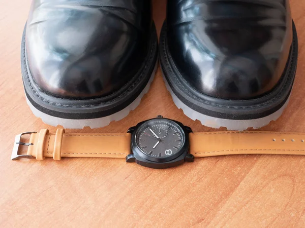 Zbliżenie Mans zegarek na nadgarstek przez parę stylowe eleganckie czarne klasyczne buty — Zdjęcie stockowe