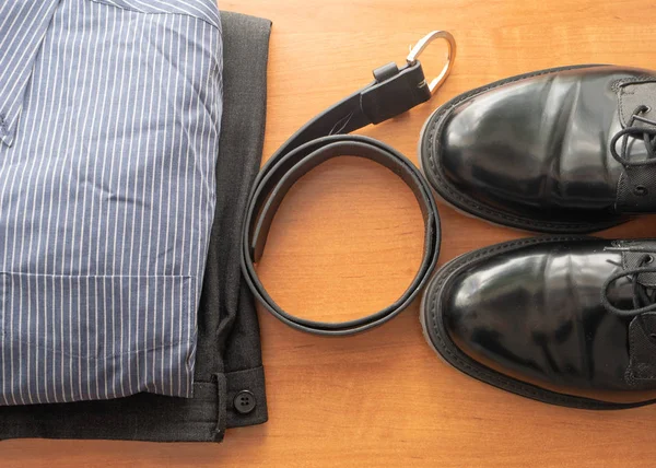 set of man businessman wear clothes on a desk - pair of black shoes, pants, shirt and leather belt