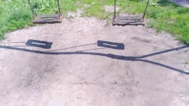 Halk parkındaki çocuk parkında iki boş salıncak. Güneşli yaz günü statik videosu