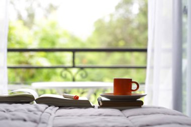 Turuncu bardak ve pencereler görünümü ile yatakta dizüstü bilgisayarlar