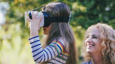 Anne, VR gözlüklerini izliyor. Kızlarla oynuyor. Küçük kız aile mutlu anları.