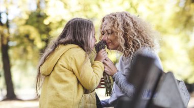 Anne ve kızı çiçekleri kokluyor aile mutlu anları seviyor anneler gününü kızlar