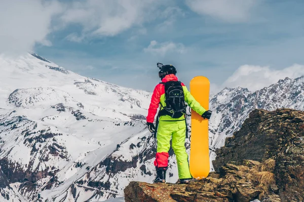 Snowboardista Oranžovým Snowboardem Stojící Skále Při Pohledu Hory Sněhu Slunečný — Stock fotografie