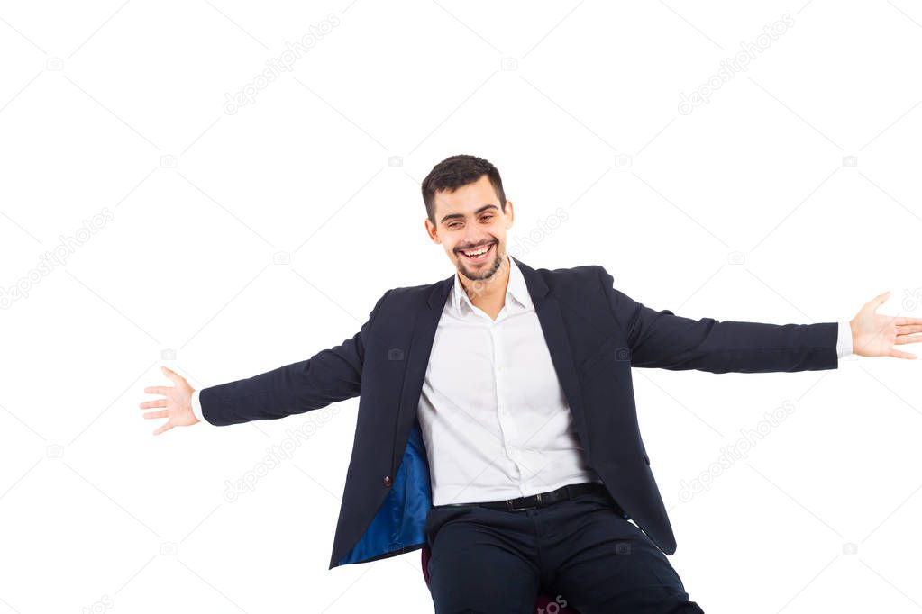 A young man stretched his arms wide apart. On the man is a business suit. He is smiling.