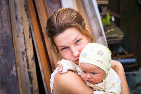 Anne ve bebek bahçede yaz bir salıncak üzerinde durmak. Kalıcı makyaj, doğal ve tedavi olmadan anne. Bebek üç aylık küçük bir kız gibi. Çocuk yawns.