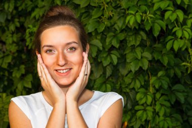 Yeşil yeşillik duvarının arka planına karşı genç kadın,