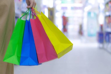 Kadın eli kapalı alışveriş torbalarını tutuyor.