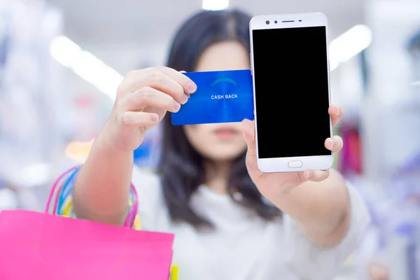 Close up woman hand holding phone, shopping bag and credit card