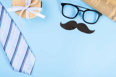 Mavi kravat, gözlük, hediye kutusu ve mavi arka planda metin için fotokopi alanı olan siyah bıyıklı Mutlu Babalar Günü konsepti.