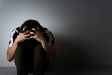 Üzgün adam dizine sarıldı ve ağladı karanlık bir odada tek başına otururken. Depresyon, mutsuz, stresli ve anksiyete bozukluğu.