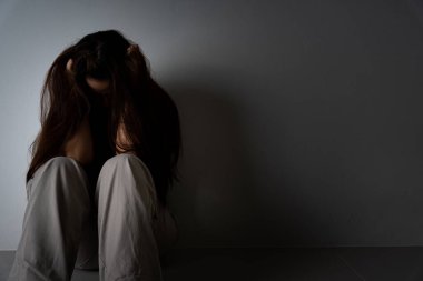 Üzgün kadın, karanlık bir odada tek başına otururken dizine sarılıp ağlar. Depresyon, mutsuz, stresli ve anksiyete bozukluğu.