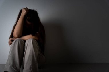 Üzgün kadın, karanlık bir odada tek başına otururken dizine sarılıp ağlar. Depresyon, mutsuz, stresli ve anksiyete bozukluğu.
