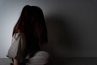 Üzgün kadın, karanlık bir odada tek başına otururken dizine sarılıp ağlar. Depresyon, mutsuz, stresli ve anksiyete bozukluğu.