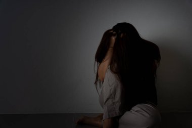 Üzgün kadın, karanlık bir odada tek başına otururken dizine sarılıp ağlar. Depresyon, mutsuz, stresli ve anksiyete bozukluğu.