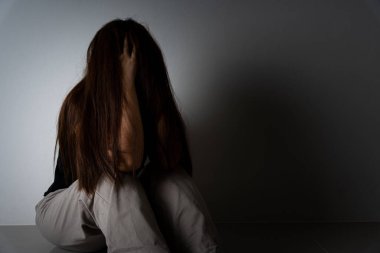 Üzgün kadın, karanlık bir odada tek başına otururken dizine sarılıp ağlar. Depresyon, mutsuz, stresli ve anksiyete bozukluğu.