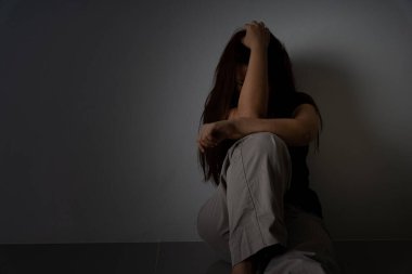 Üzgün kadın, karanlık bir odada tek başına otururken dizine sarılıp ağlar. Depresyon, mutsuz, stresli ve anksiyete bozukluğu.