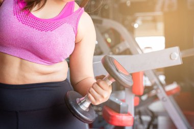 Dambıl tutan şişman kadın ve aşırı şişman göbek fitness salonunda şişman göbek. Diyet yaşam tarzı, kilo kaybı, mide kası, sağlıklı konsept.
