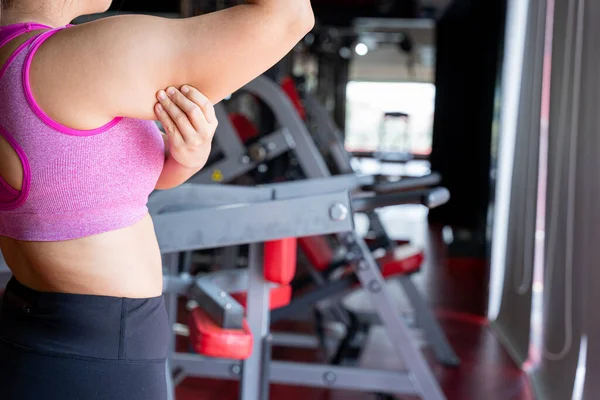 Woman holding hand excessive fat arm at gym. Woman pinching arm fat flabby skin. Weight loss, slim body, healthy lifestyle concept.