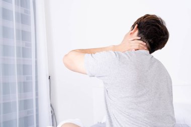 Rahatsız yataktan dolayı boyun ve omuz ağrısı çeken genç bir adam. Sağlık hizmeti tıbbi veya günlük yaşam konsepti.