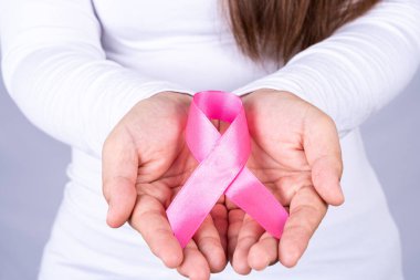 Kızıl AIDS farkındalık kurdelesi gri arka plandaki adamın elinde. Dünya Yardım Günü, Sağlık ve Tıbbi Konsept.