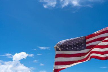 Mavi arka planda ABD bayrağı sallıyor.