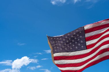 Mavi arka planda ABD bayrağı sallıyor.