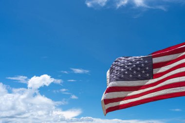 Mavi arka planda ABD bayrağı sallıyor.