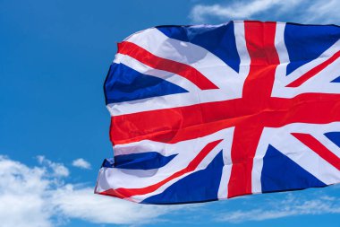Mavi gökyüzü arkaplanı altında İngiliz bayrağı sallanıyor.