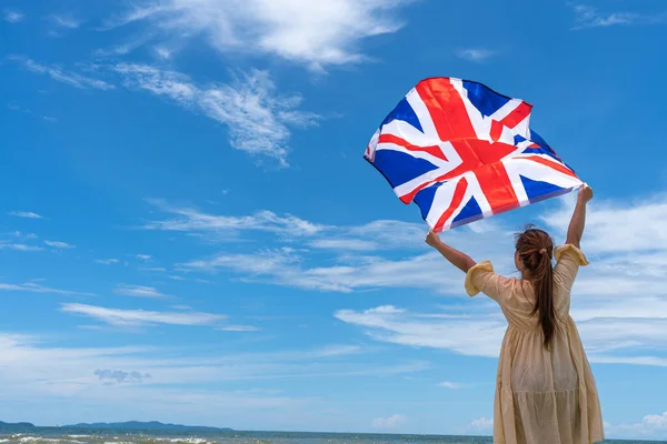 Kobieta Stojąca Trzymająca Brytyjską Flagę Pod Błękitnym Niebem — Zdjęcie stockowe