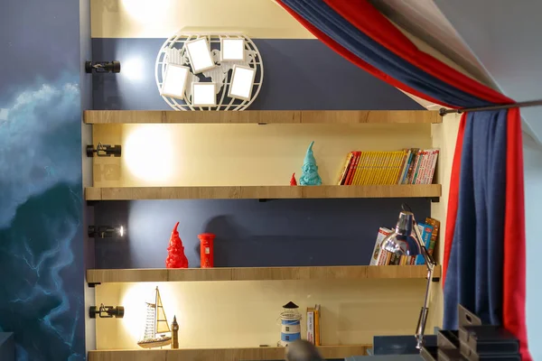 Kitaplarla, çocuk oyuncaklarıyla dolu bir kitaplığın içine inşa edilmiş. Raftaki fotoğraf çerçeveleri, resimlerinizi ekleyebilirsiniz. Kırmızı mavi perde.