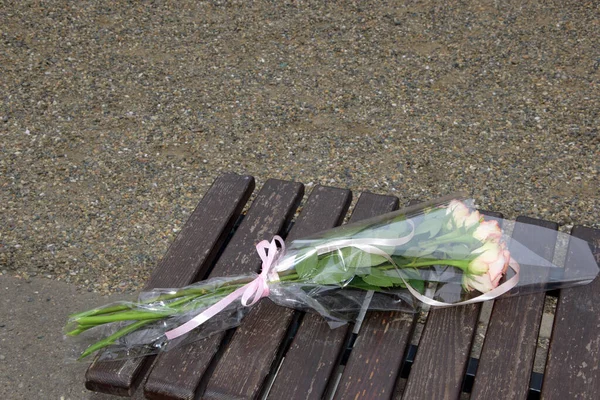 一把废弃的粉红色玫瑰束放在木制长椅上 争吵并尝试以牺牲爱人的原谅为代价送花的概念 — 图库照片