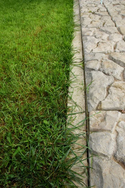 Um limite claro entre a alvenaria de pedra e o gramado verde. — Fotografia de Stock